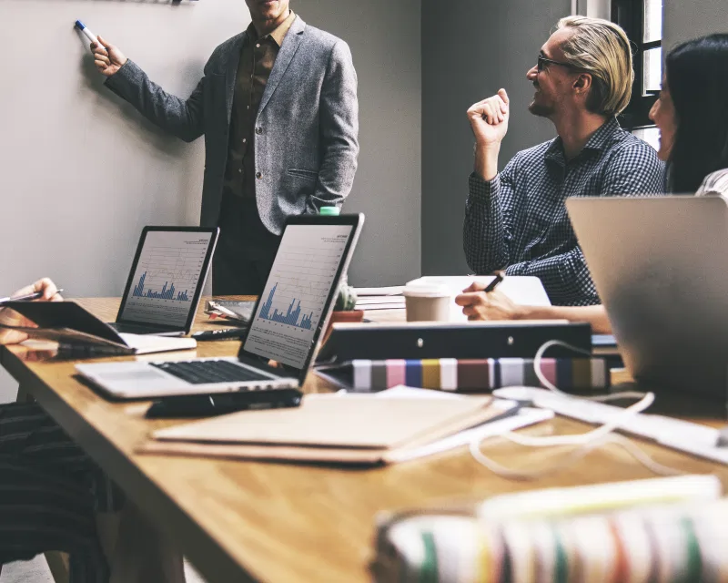 An expert providing corporate housekeeping services by outlining a business strategy on a whiteboard.