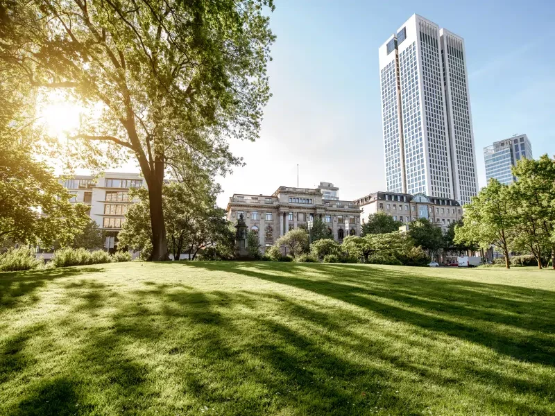 A modern corporate building viewed from a park, representing the high-value assets managed by our private equity and venture capital services.