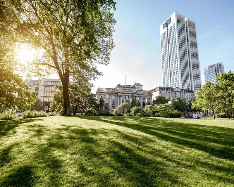 A modern corporate building viewed from a park, representing the high-value assets managed by our private equity and venture capital services.