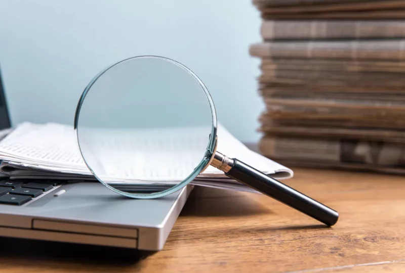 Magnifying glass on a document representing clear answers to common questions in our German shelf company FAQ.
